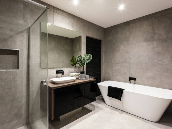Modern bathroom with a shower area and bath tub including a wall mirror beside a fancy plant near a tap and sink over the wooden counter and dark cupboard; Shutterstock ID 450627787; purchase_order: -; job: -; client: -; other: -